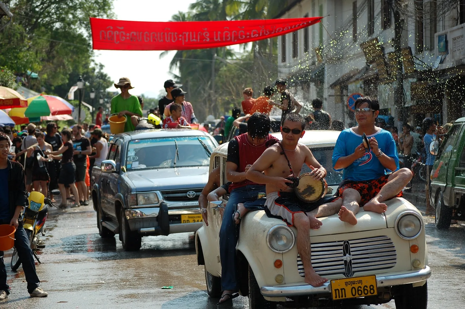 Revellers sit on vehicle hoods playing drums during a street water festival in Luang Prabang.